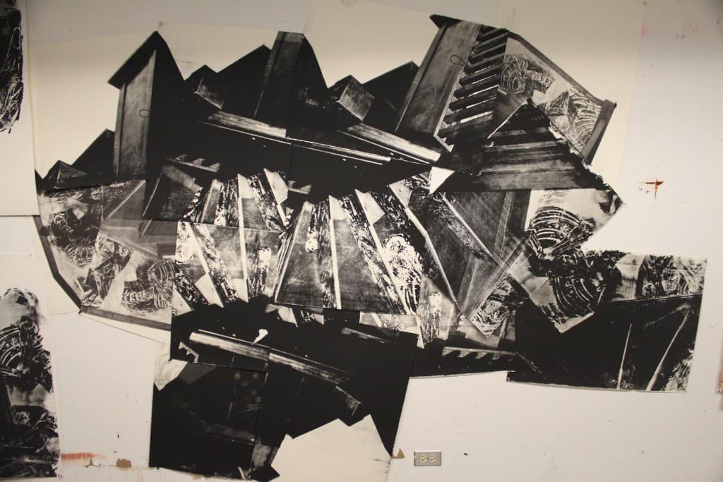 Large-scale black and white collage installation: fragmented photographic prints arranged on a studio wall